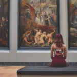 Museums - Woman Sitting on Ottoman in Front of Three Paintings