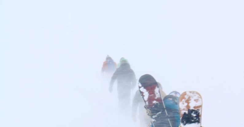 Hiking Tours - Snowboarders Walking in Snowstorm